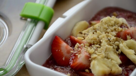 Komosa ryżowa z truskawkami, bananami i orzechami włoskimi spakowana do lunchboxu.