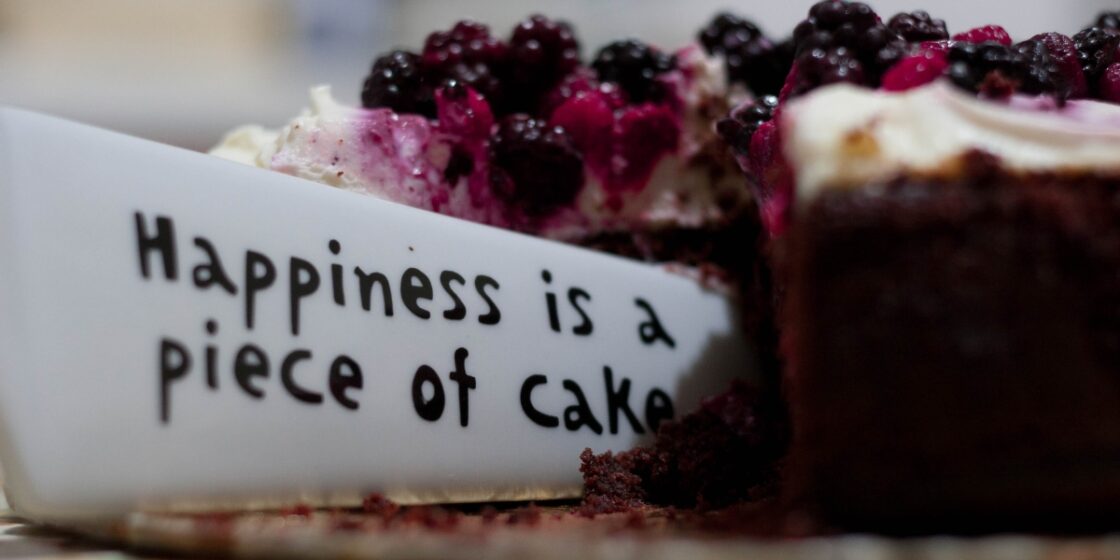 Tort owocowy z wbitym napisem "Hapiness is a piece of cake" - szczęście to kawałek ciasta!